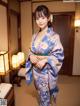 A woman in a blue kimono standing in a room.