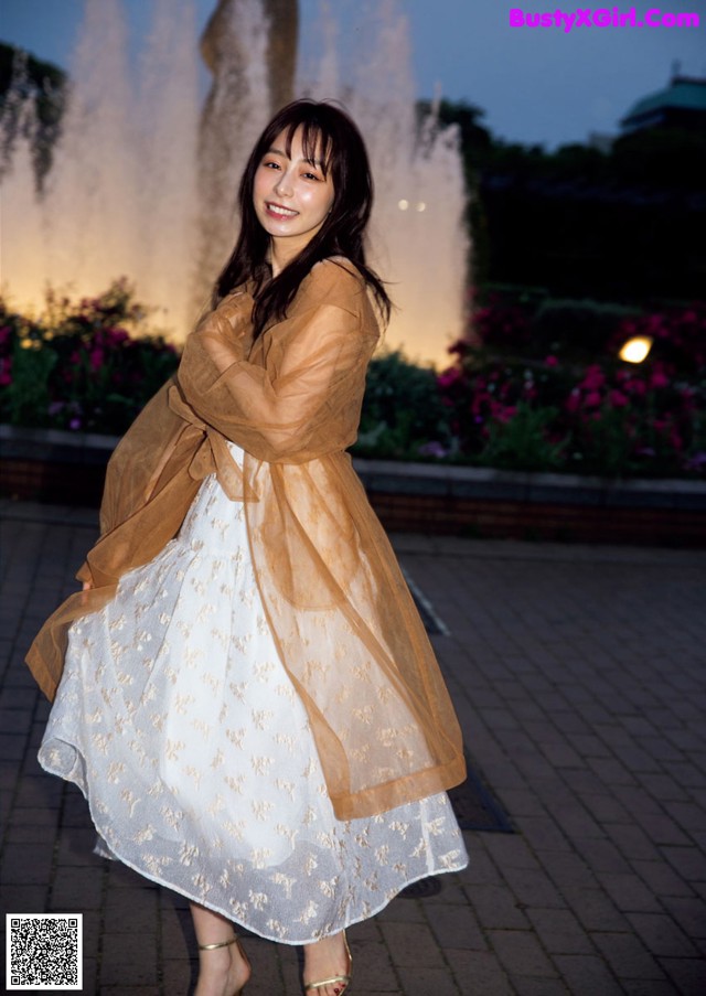 A woman standing in front of a fountain at night.