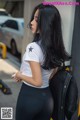 A woman in a white shirt and black leggings with a backpack.