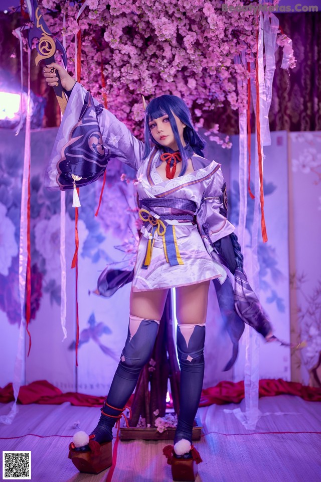 A woman in a kimono holding a sword in front of a tree.