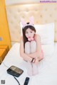 A woman sitting on a bed wearing bunny ears.