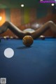 A woman laying on top of a pool table next to a pool ball.