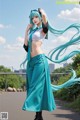 A woman with long blue hair wearing a long skirt and a white top.
