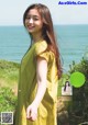 A woman in a yellow dress standing on a beach.