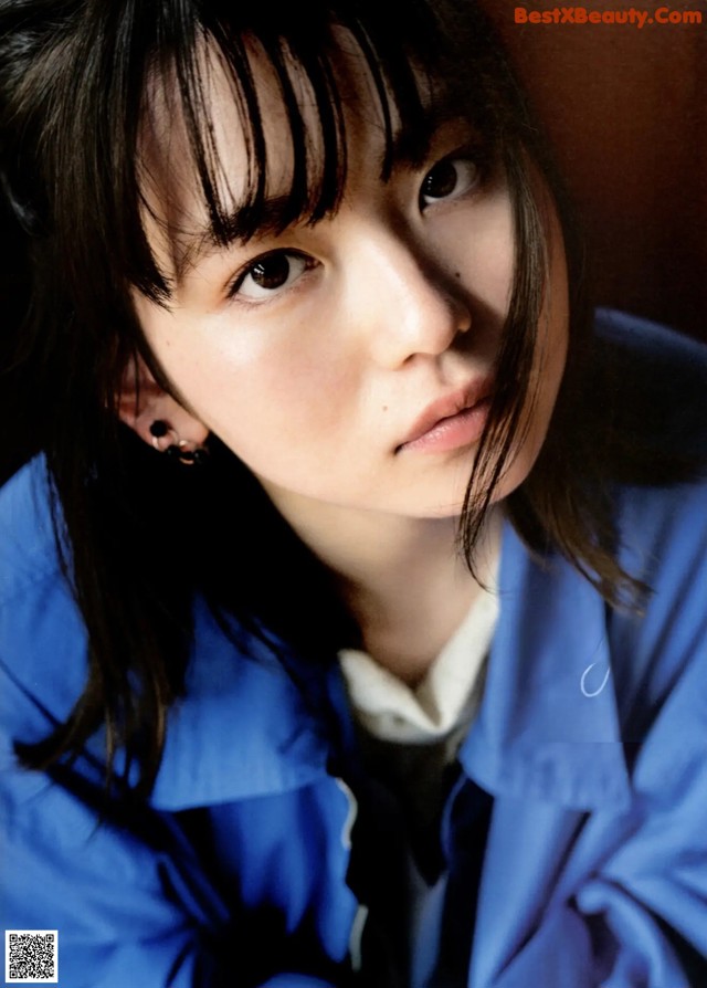 A woman with long black hair wearing a blue jacket.