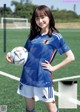 A woman holding a soccer ball on a soccer field.