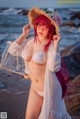 A woman in a white bikini and a straw hat on the beach.