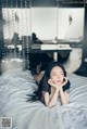 A woman laying on a bed with her hand on her chin.