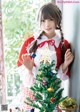 A woman in a red and white dress holding a Christmas tree.