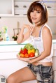 A woman holding a plate of vegetables in a kitchen.