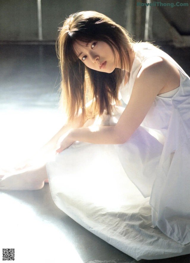 A woman in a white dress sitting on the floor.