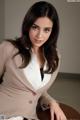 A woman in a business suit sitting on a table.