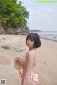 A woman in a red and white bikini standing on a beach.