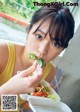 A woman eating a salad with a fork in her mouth.