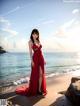 A woman in a red dress standing on a beach.